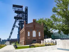 Dawna kopalnia w centrum miasta, idealne miejsce, by zobaczyć, co zwiedzić na Śląsku. Wieża szybu i ceglany budynek tworzą industrialny krajobraz.
