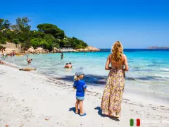 Sardynia najpiękniejsze miejsca: rodzina cieszy się słońcem i krystalicznie czystą wodą na piaszczystej plaży.