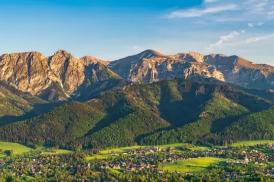 Góry Tatry o zachodzie słońca, idealne na plan "Zakopane w 3 dni co zwiedzić". Widok na miasto i zielone zbocza.